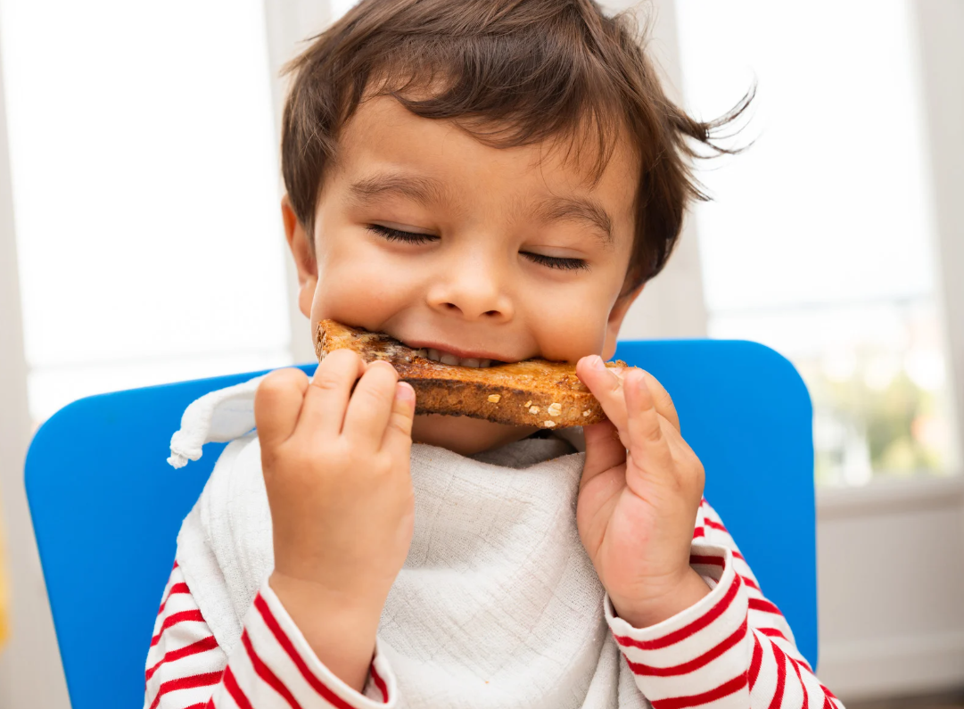 A toddler enjoying their food, as part of food phase development.